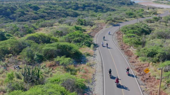 Group of bikers on Puntarena coastal road in Dominican Republic. Aerial follow