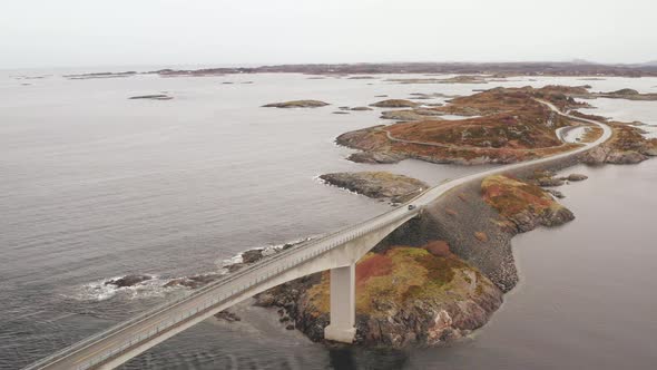 Car Crossing The Famous Storseisund Bridge On Atlantic Ocean Road On a Cloudy Day, Norway. -Aerial O