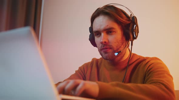 Portrait of Young Man with Headset Working on Laptop