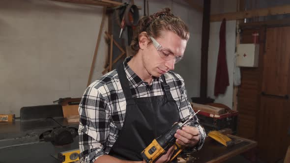 Craftsman with Electric Drill in Hands Standing in Workshop