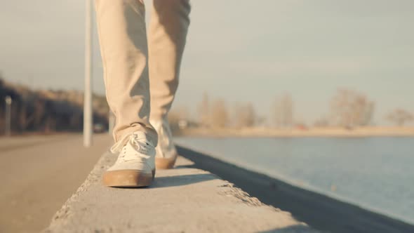 Man In Pants Stroll Near River. Man Feet Walking In City. Man Legs In Shoes Walking On Parapet.