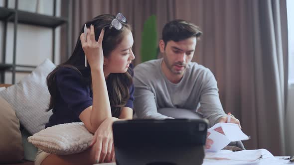 young asian caucasian couple checking bills,discussing planning budget together