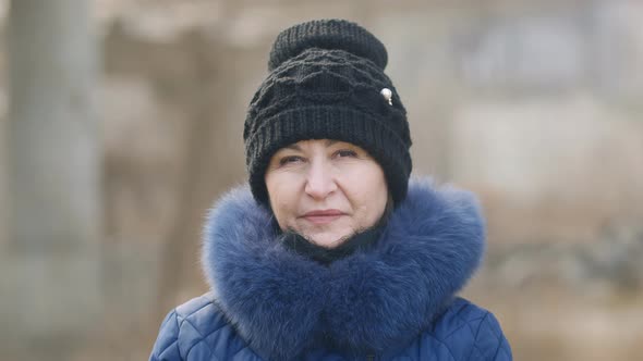 close-up Beautiful caucasian woman in a black stylish hat with a blue fur collar smiles and looks at