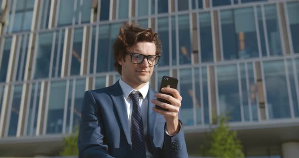 Medium Shot of Young Businessman Using Mobile Phone Standing on Street