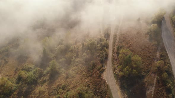 Aerial Drone Flight View Over Low Clouds and Morning Mist Covered Mountain Slopes at Sunrise