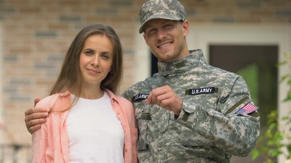 Happy Army Veteran Hugging Wife Holding House Key Standing Outside Cottage