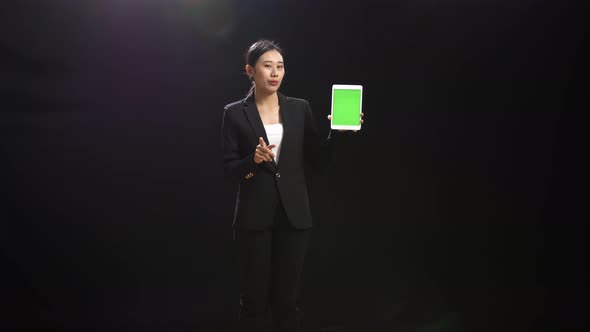 Asian Speaker Woman Holding And Pointing Green Screen Tablet While Speaking On Stage