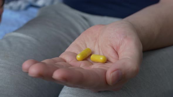 Two Gelatin Capsules with Medicines are Poured Into the Palm of your Hand