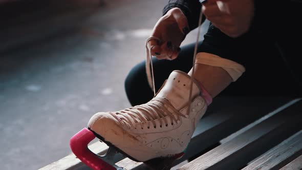 A Young Woman Ties Shoelaces on White Skates