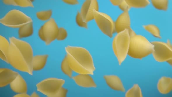 Pasta Conchiglie is Falling Diagonally on a Blue Background