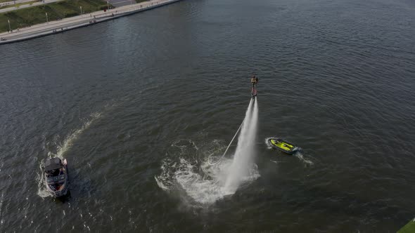 A Man with a Girl Flies Over the River on a Flyboard and Dives Into the Water