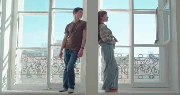 Man and a Woman are Standing Through the Partition on the Windows