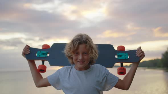 Silhouette Happy Child Portrait of Young Stylish Skater Boy Holding His Skateboard Outdoors