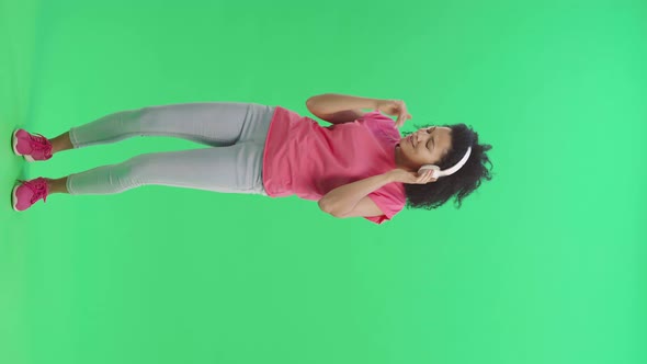 Portrait of Young Female African American Dancing and Enjoying Music in Big White Headphones