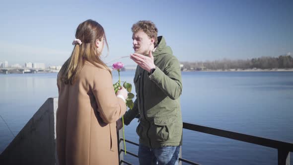 Young Caucasian Couple Arguing Outdoors. Nervous Chubby Girl Returning Pink Rose To Man and Leaving