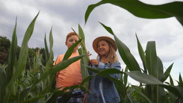 Cute Girl Holding in Hand Cornstalk and Telling Something Her Friend While Going Among Maize