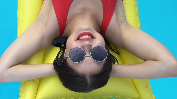 Smiling Pretty Lady Enjoying Vacation on Inflatable Mattress in Swimming Pool