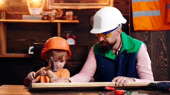 Dad Shows His Son How To Make Diy in Wooden Workshop Using Hammer and Nail.