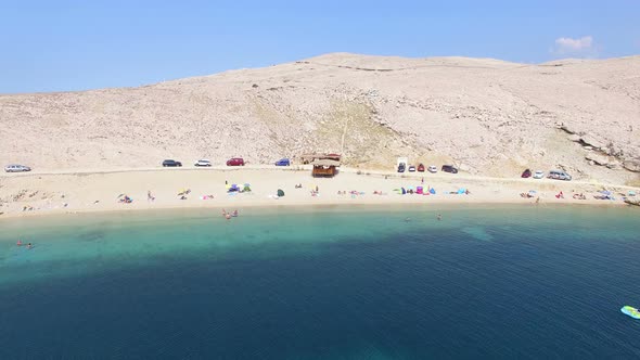 Flying above tourists on isolated beach of Pag island, Croatia alt