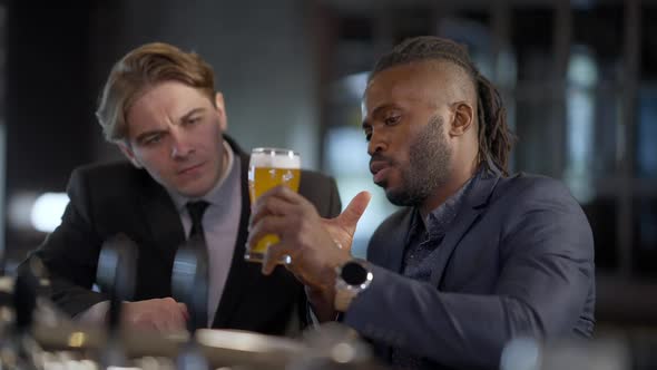 African American Beer Connoisseur Talking with Caucasian Friend Explaining Pale Lager Features