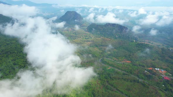 4K Aerial view from a drone flying above rural clouds, road in a tropical forest in Thailand