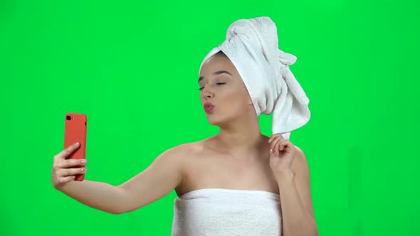 Spa Woman in White Towel on Her Head Makes Selfie with Red Cellphone Isolated on Green Screen. Slow