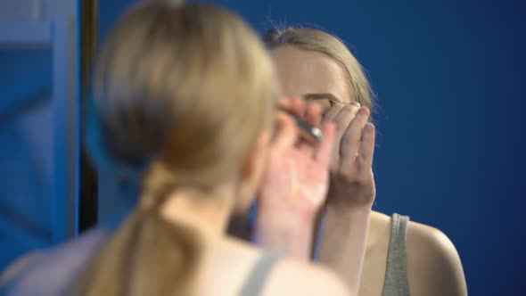 Female Student Feeling Pain While Plucking Eyebrow With Tweezers, Beauty Routine