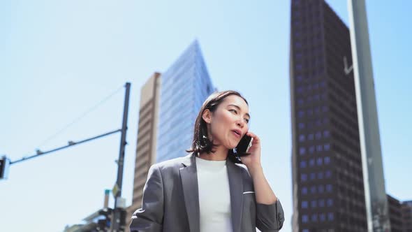 Confident Asian Business Woman Wearing Suit Making Call Standing in Big City