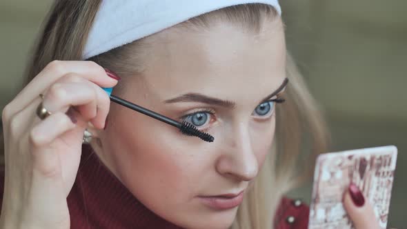 Beautiful Blonde Girl Paints Her Eyelashes.