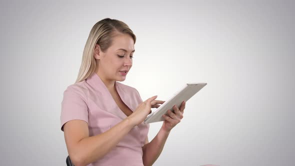 Woman Sitting Watching Tablet Pc and Smiling on Gradient Background