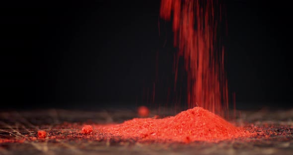 Ground Red Chili Pepper Drops on Wooden Table.