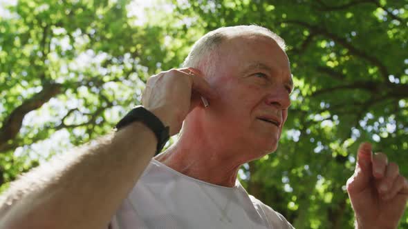 Senior man using wireless earphones in the park