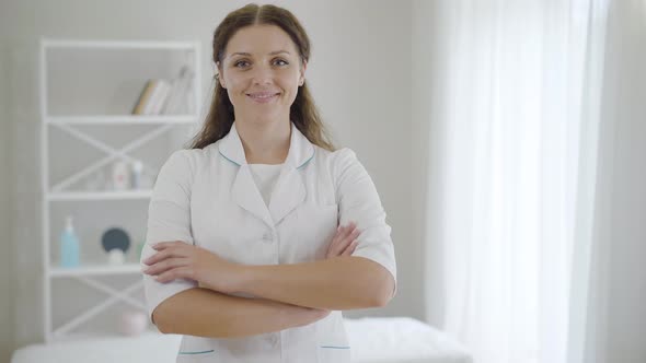 Portrait of Confident Beautiful Doctor Crossing Hands and Smiling at Camera. Young Charming