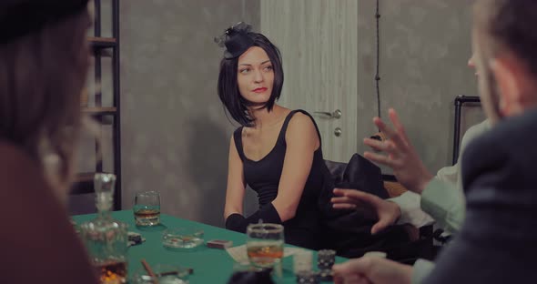 Rich Beautiful Woman in a Hat Sits at the Playing Table