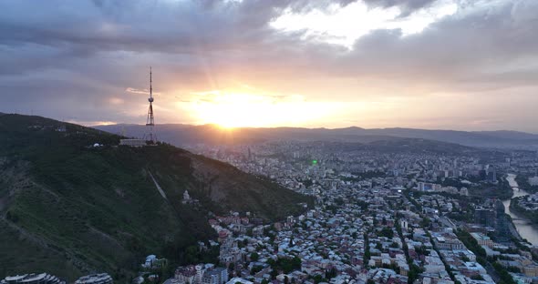 Aerial view of center of Tbilisi under Mtatsminda mountain at sunset. Georgia 2022 summer