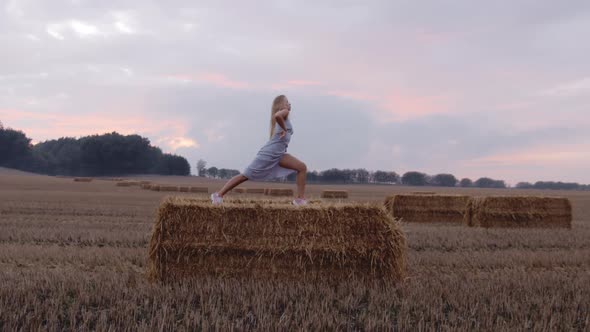 A Female Blonde Model Stretching on Top Of a Haystack
