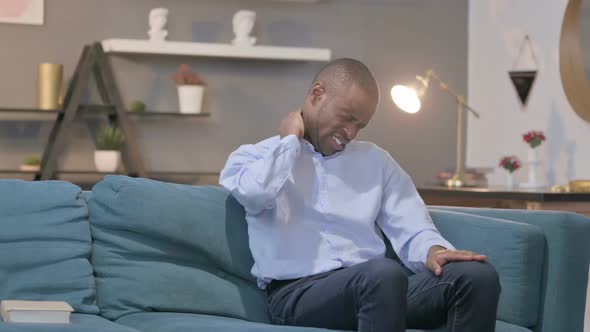 African Man Having Neck Pain While Sitting on Sofa