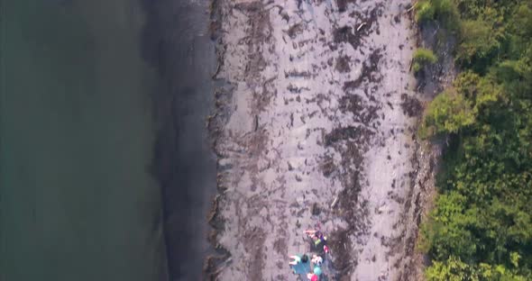 Aerial shot flying over a sandy beach with people walking below enjoying the Atlantic Ocean waves la