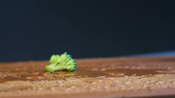 Delicious Fresh Broccoli Pieces Fall Down on Brown Board