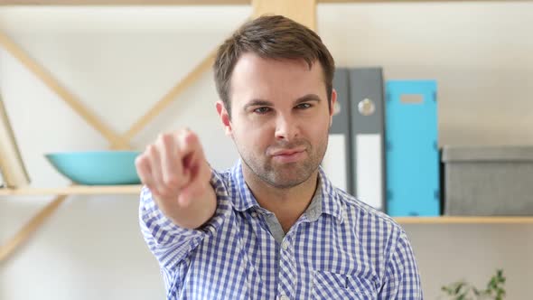 Man Pointing at Camera Sitting in Office