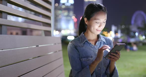 Asian woman use of mobile phone in the city at night 