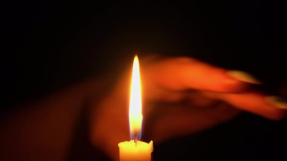 Woman Runs Her Hand Through the Flame of a Yellow Candle