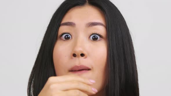 Portrait Of Shocked Chinese Woman Eating Popcorn Over White Background