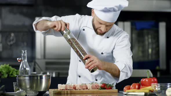 Male Chef Peppering Meat at Kitchen. Closeup Chef Peppering Steak at Workplace