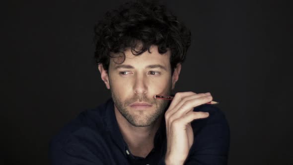 Man holding pencil with bored expression on face