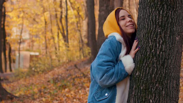 Young Woman Hugs Tree in Autumn Forest