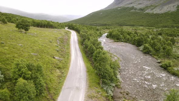 Black Car Travelling On The Mountain Road With Stream And Lush Green Trees In Hydalen Valley, Hemsed