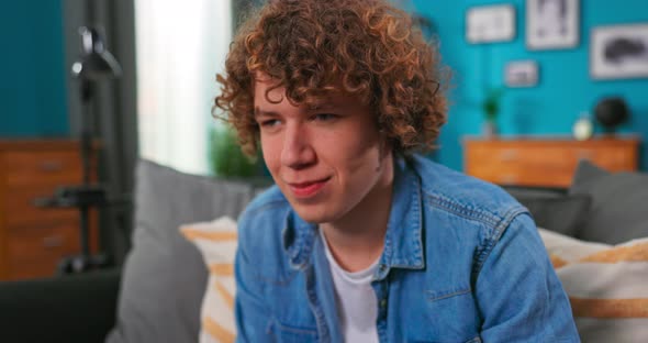 Portrait of Young Handsome Gamer Boy Sitting on Sofa and Playing in Video Games on