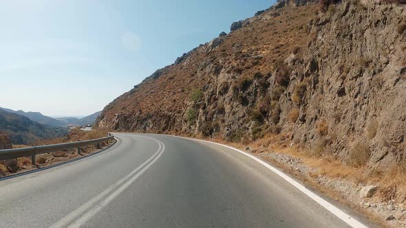 POV Driving a car on curvy asphalt road with rocky mountains near Grand Canyon. Blue sky with white