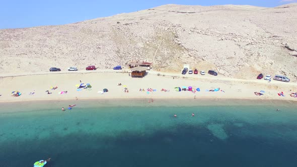 Flying above tourists on quiet family beach on Pag island, Croatia